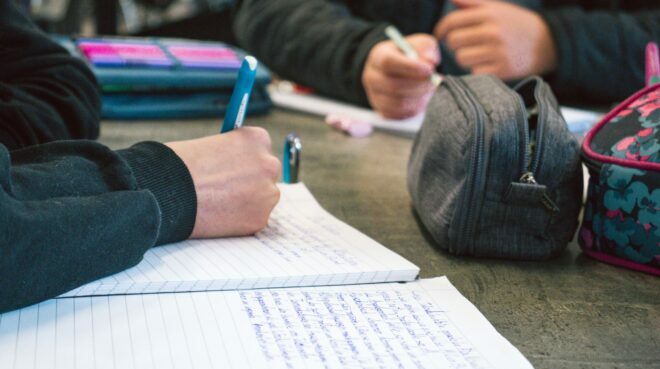 Tisch mit Teilnehmer*innen der Schreibwerkstatt; Kinder beim Schreiben